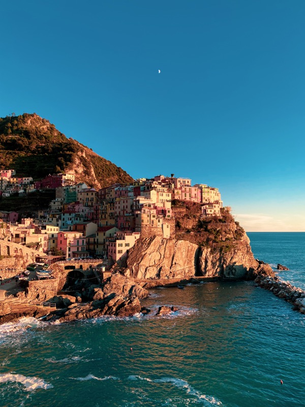 Colorful houses of Manarola on a cliff side during golden hour